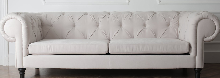 Белый диван на коричневых ножках в комнате со светлыми стенами